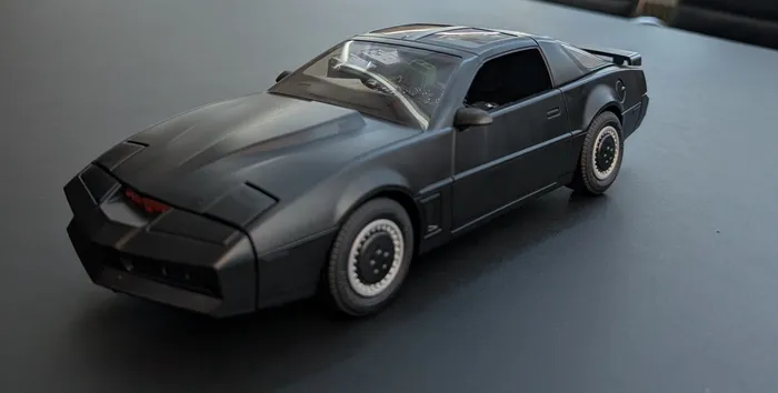 A black K.I.T.T. toy car from Knight Rider on a dark table